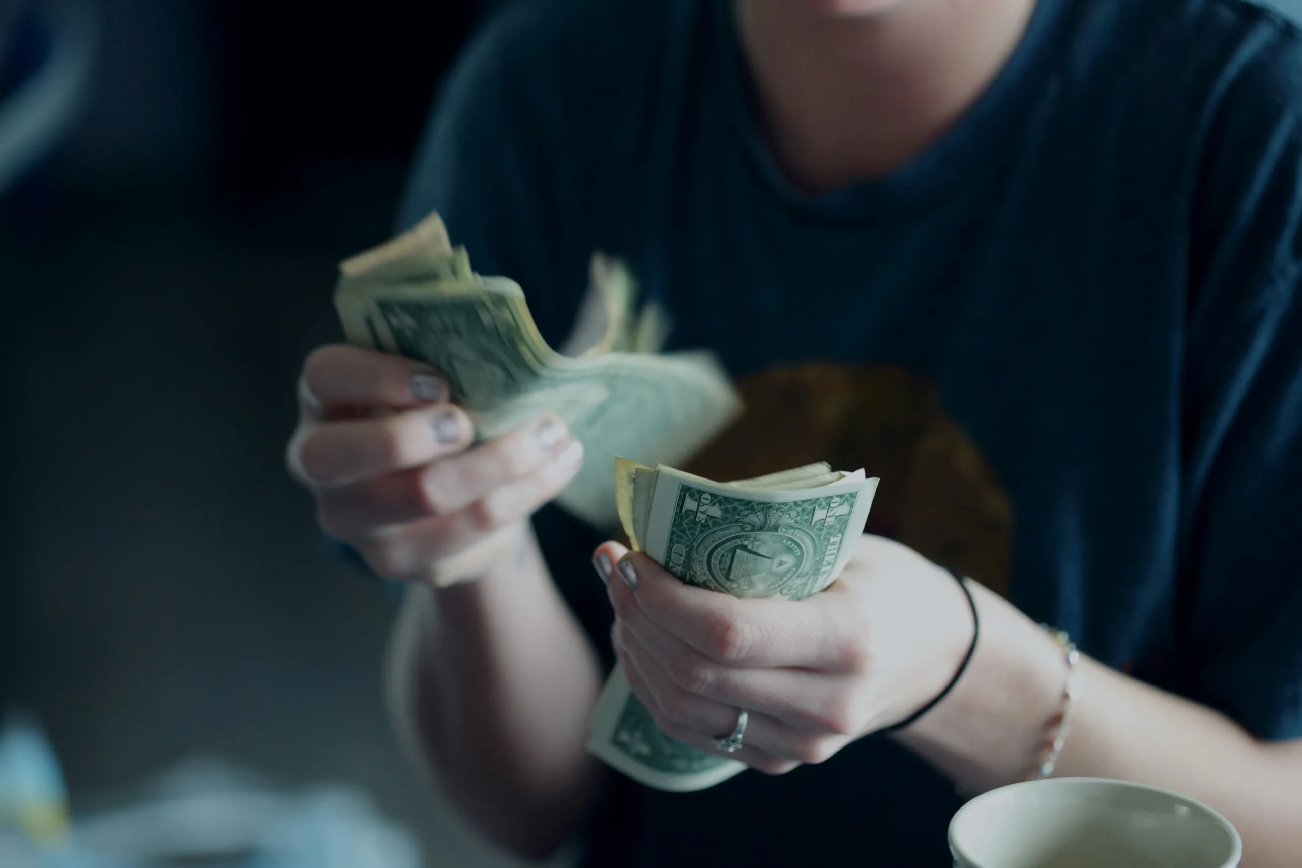 A woman counting a stack of U.S. dollar bills.