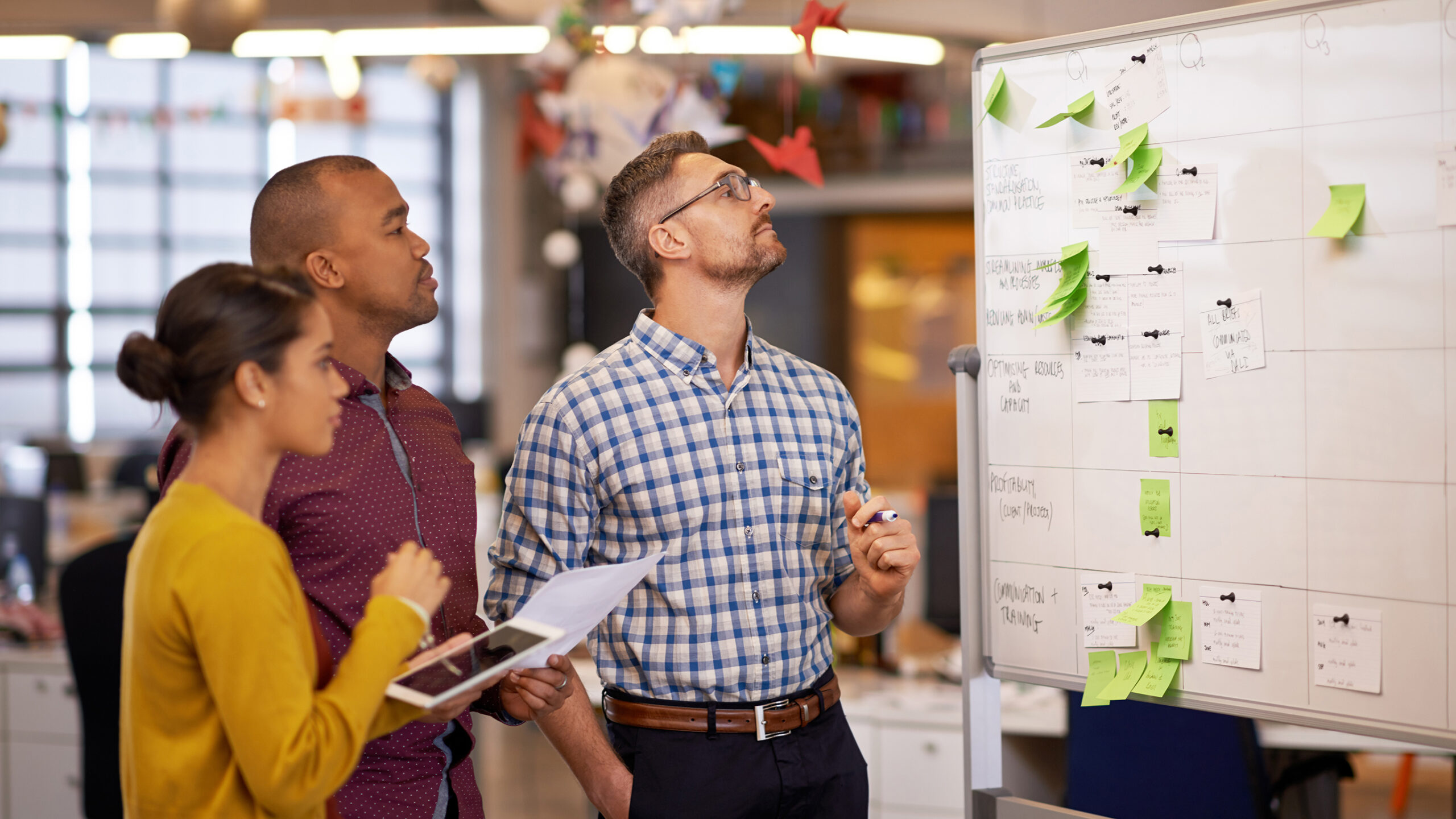 Whiteboard, thinking and business people with optimisation strategy in a office. Startup, company training and creative writing group with communication and vision with ideas and writer sticky notes